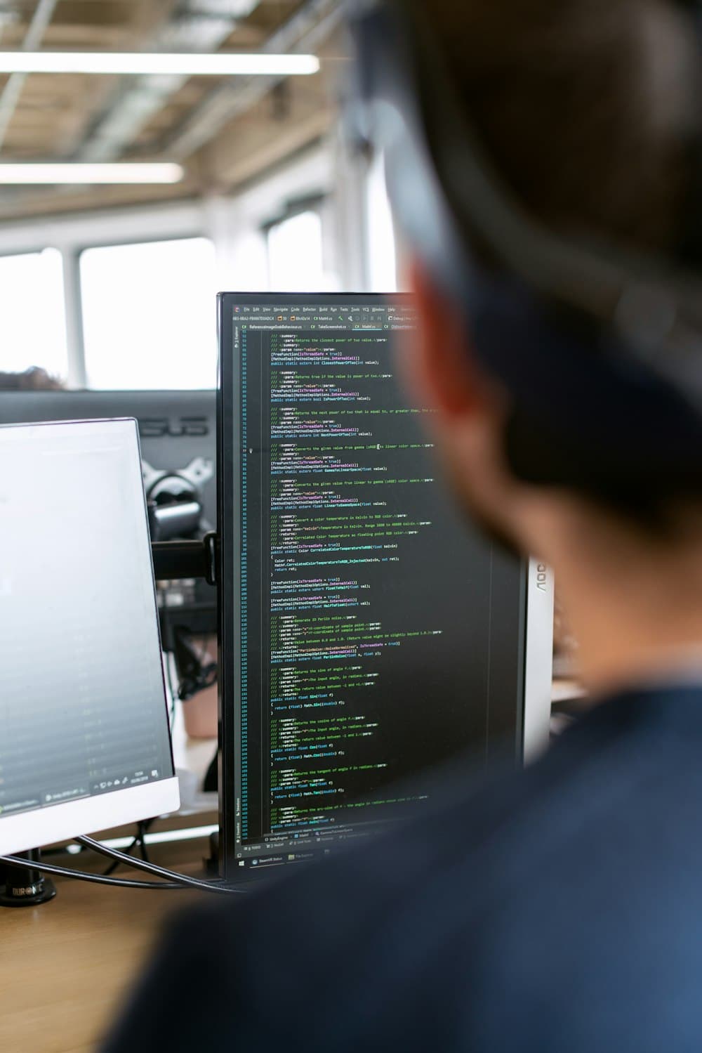 A TotalTech engineer working on production code at a multi-monitor workstation